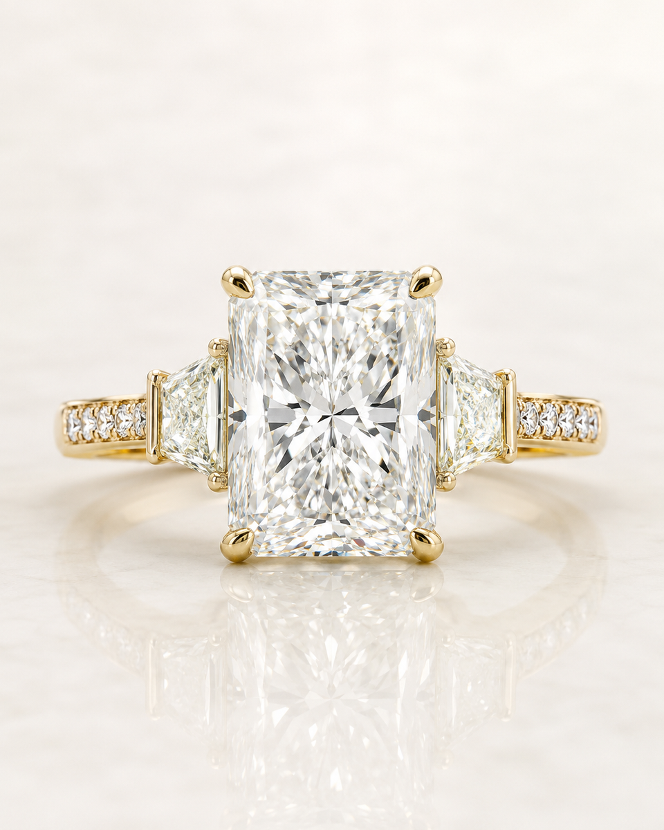 Radiant-cut three-stone engagement ring in yellow gold with trapezoid side stones and a pavé band — design rendering