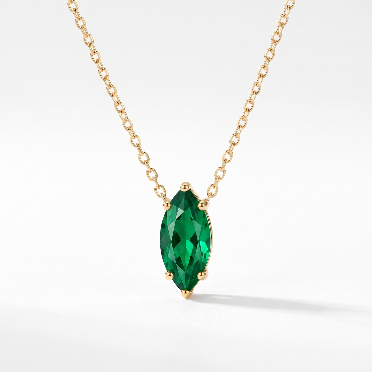 Marquise-cut emerald solitaire necklace in solid gold, catalog view — AI-generated design representation