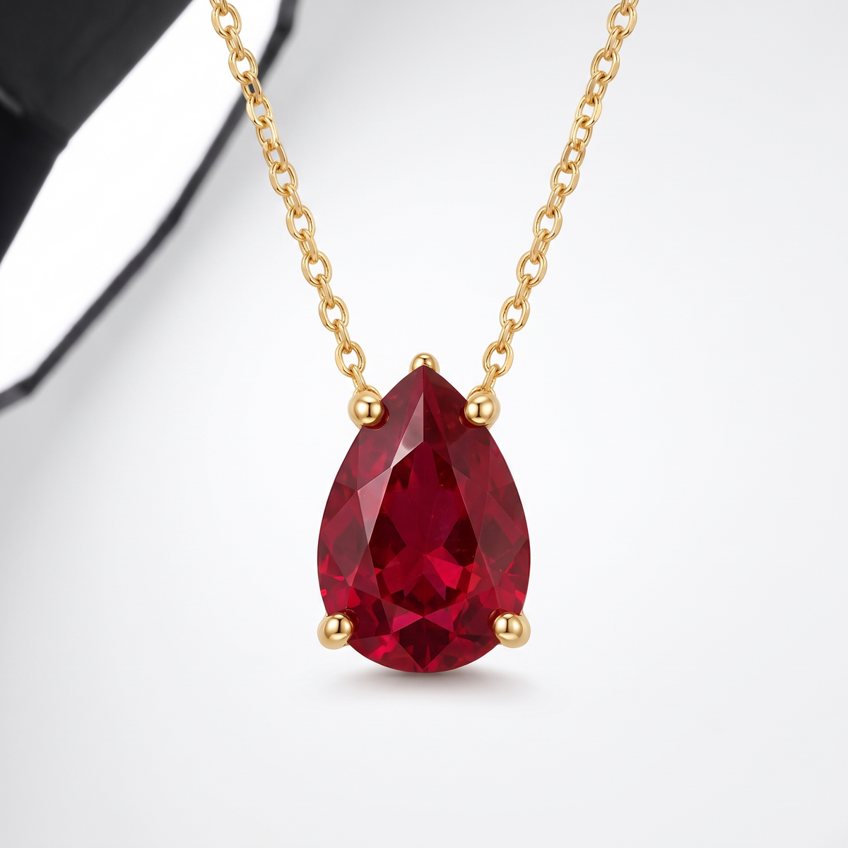 Pear-cut ruby solitaire necklace in solid gold, catalog view — AI-generated design representation