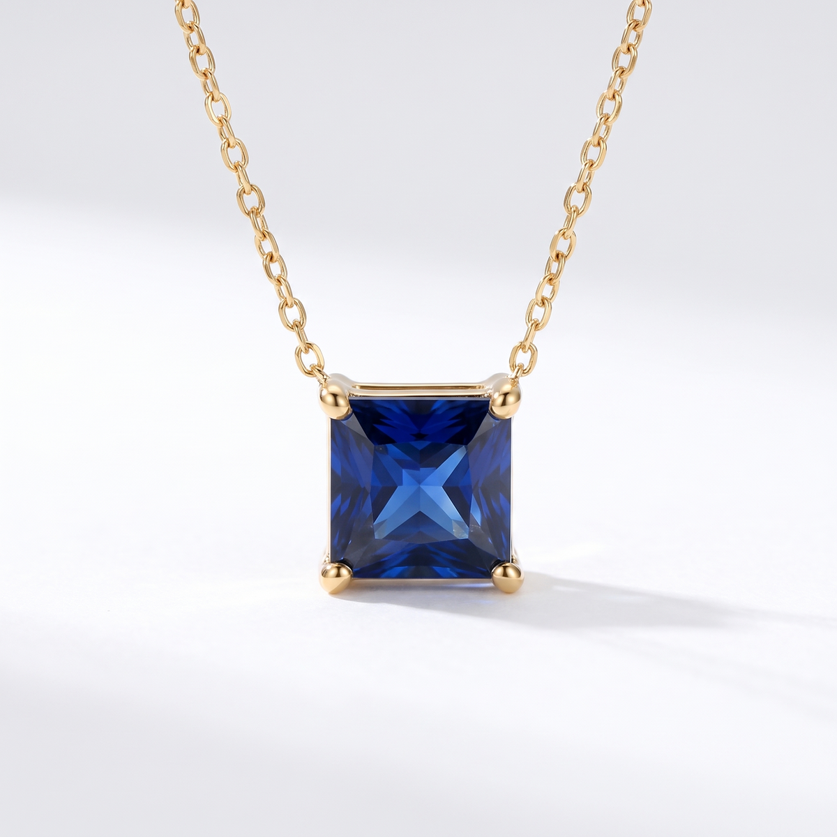 Princess-cut blue sapphire solitaire necklace in solid gold, catalog view — AI-generated design representation