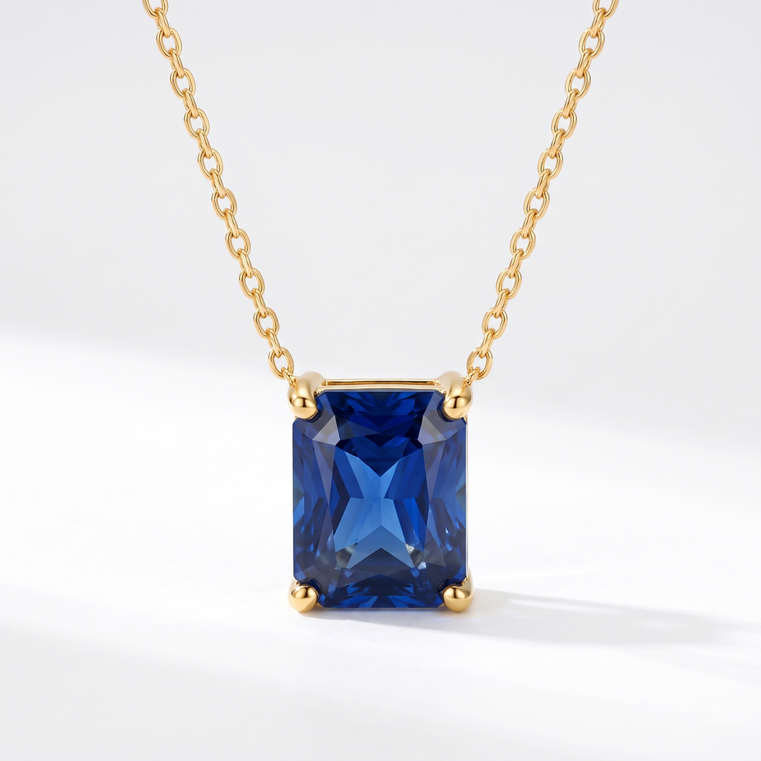 Radiant-cut blue sapphire solitaire necklace in solid gold, catalog view — AI-generated design representation