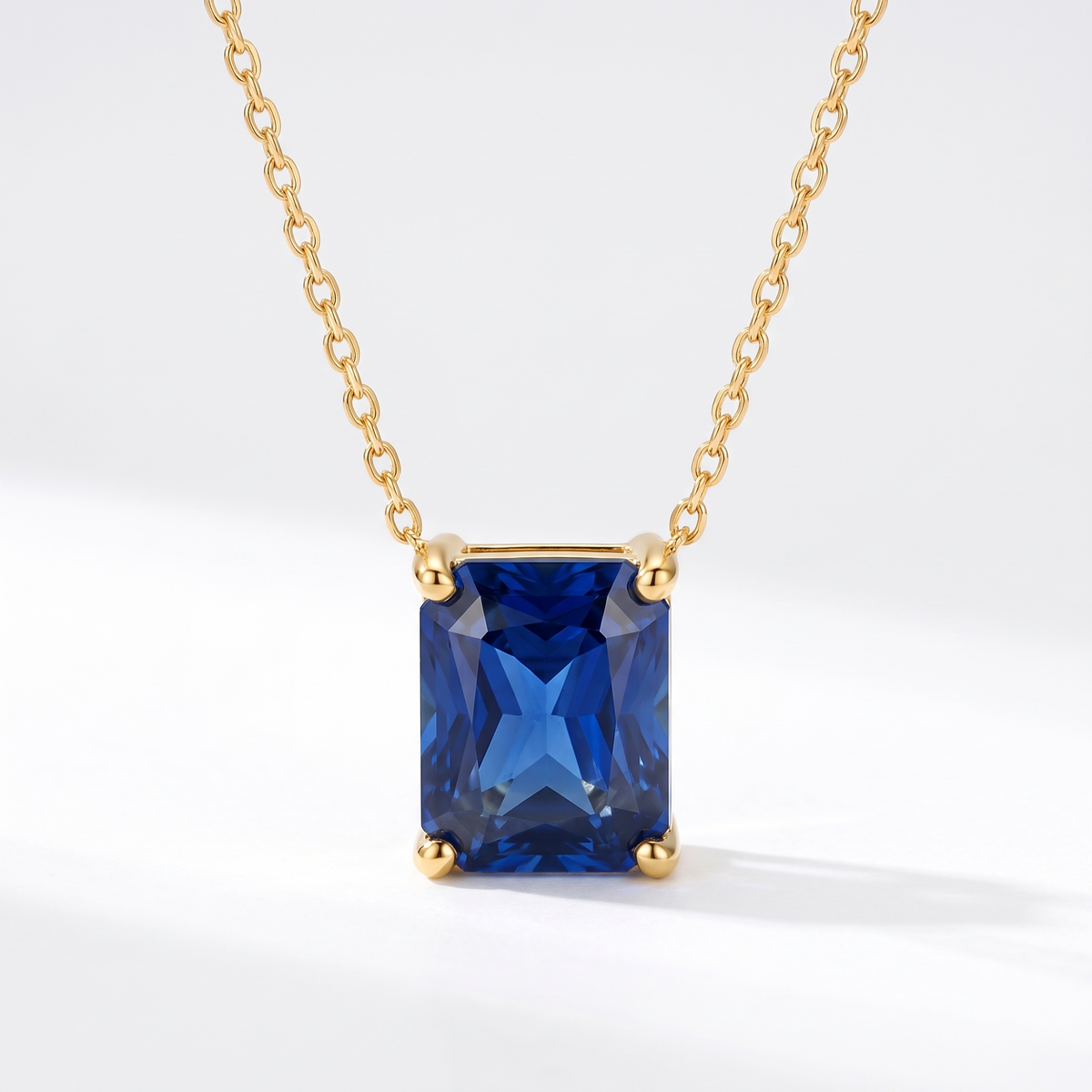Radiant-cut blue sapphire solitaire necklace in solid gold, catalog view — AI-generated design representation