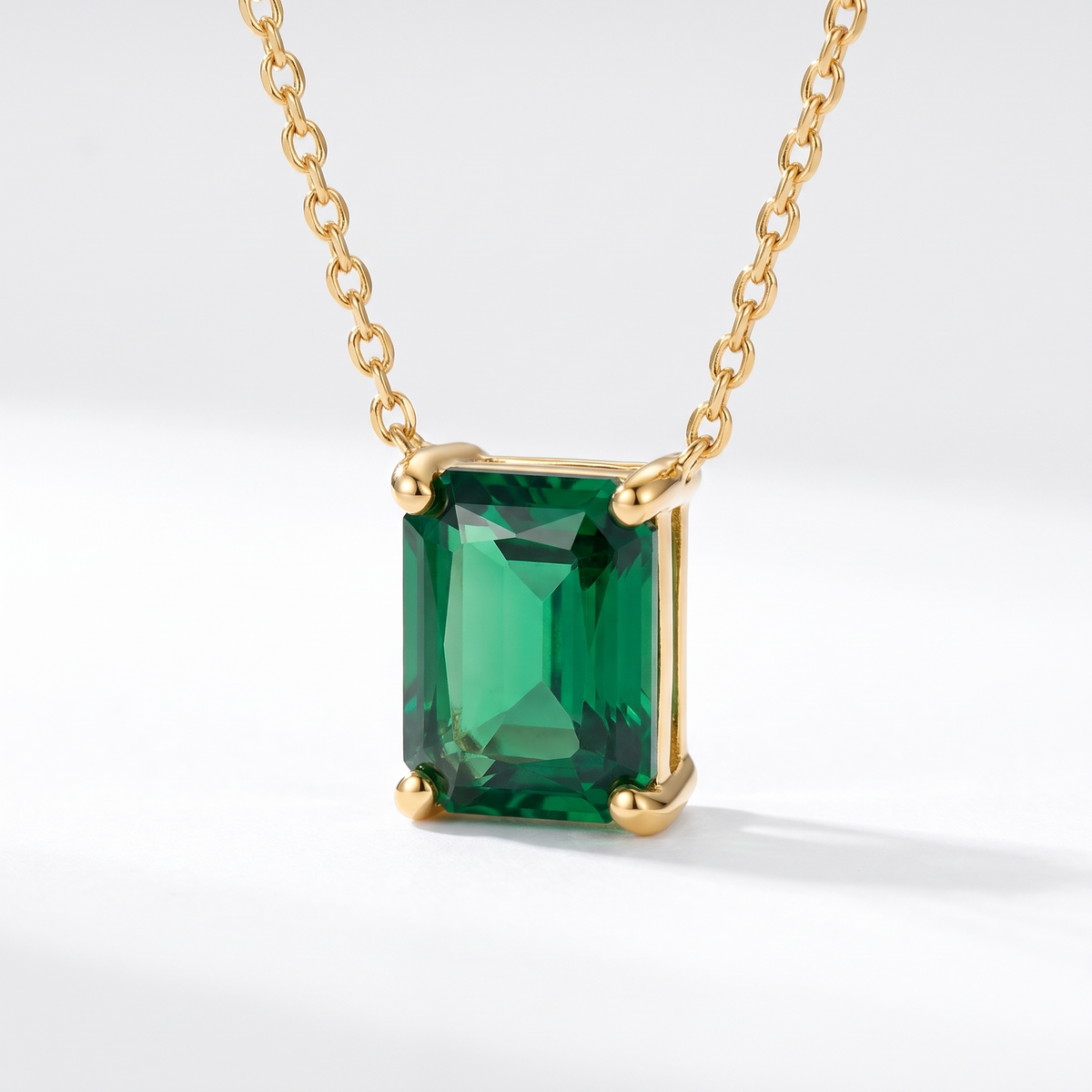 Radiant-cut emerald solitaire necklace, angled front detail — AI-generated design representation