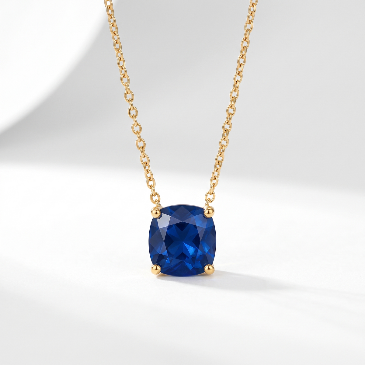 Cushion-cut blue sapphire solitaire necklace in solid gold, catalog view — AI-generated design representation