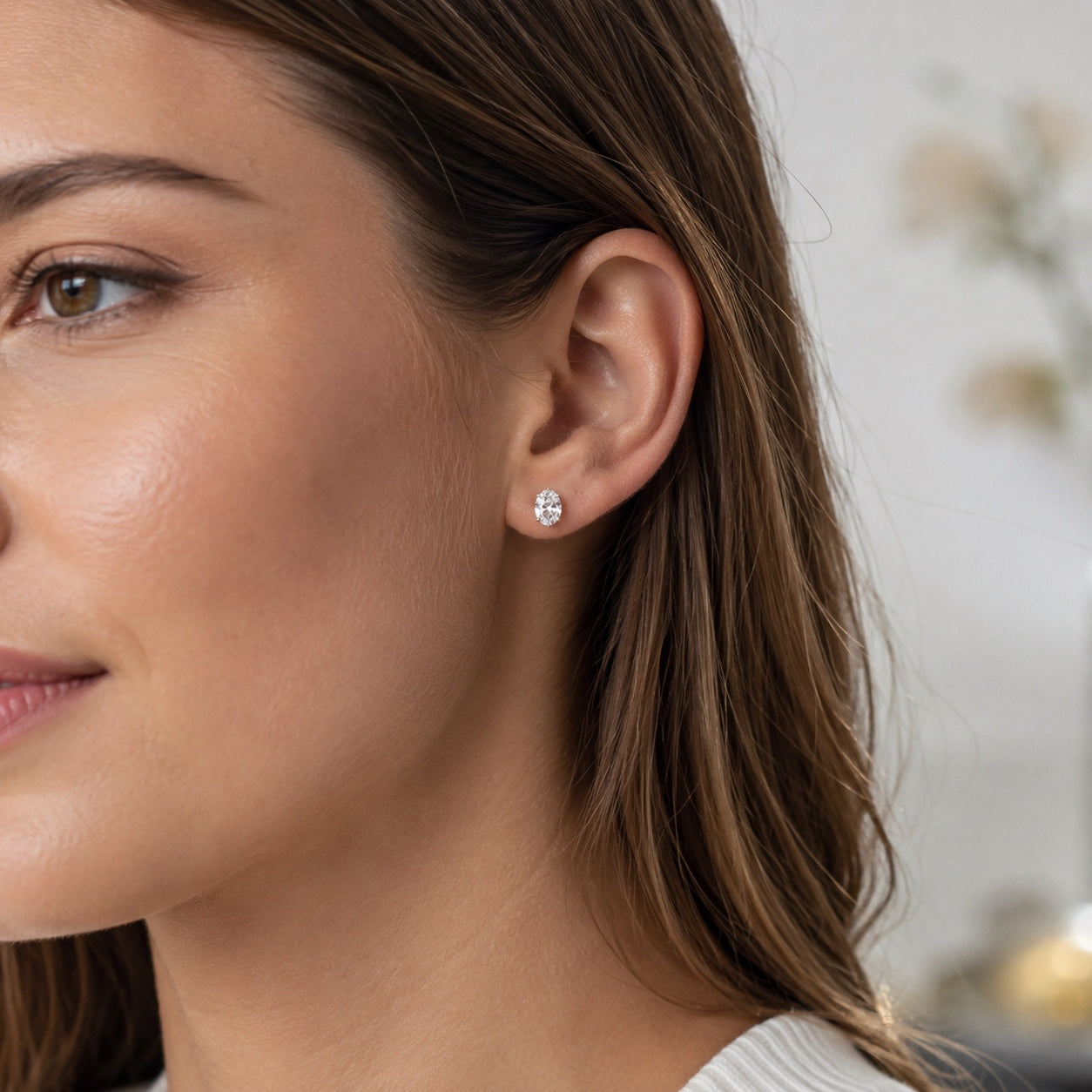 Design render of a woman wearing oval 1.00 CTW lab-grown diamond stud earrings in 14K white gold