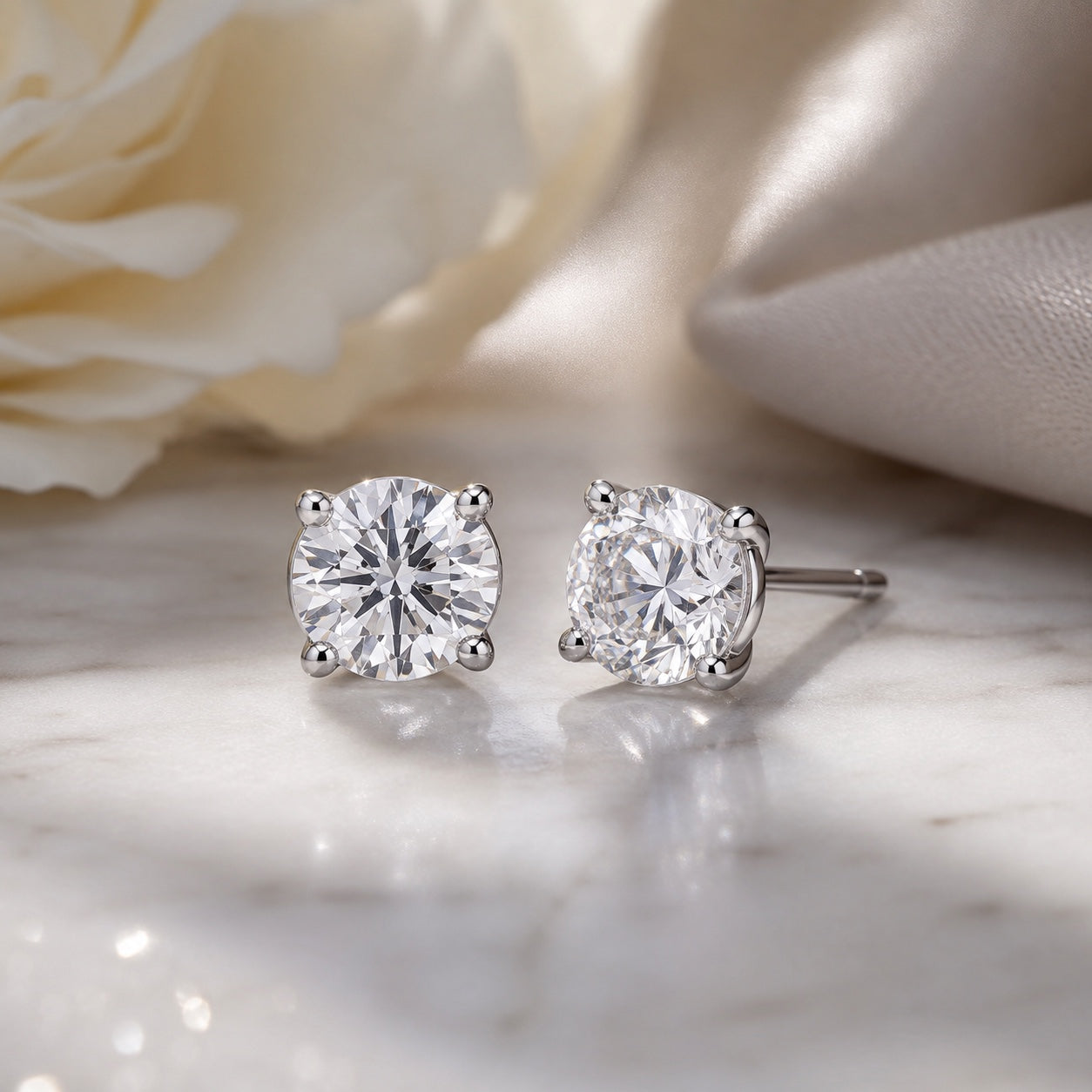 Editorial design render of round 0.50 CTW lab-grown diamond studs in 14K white gold on marble and silk